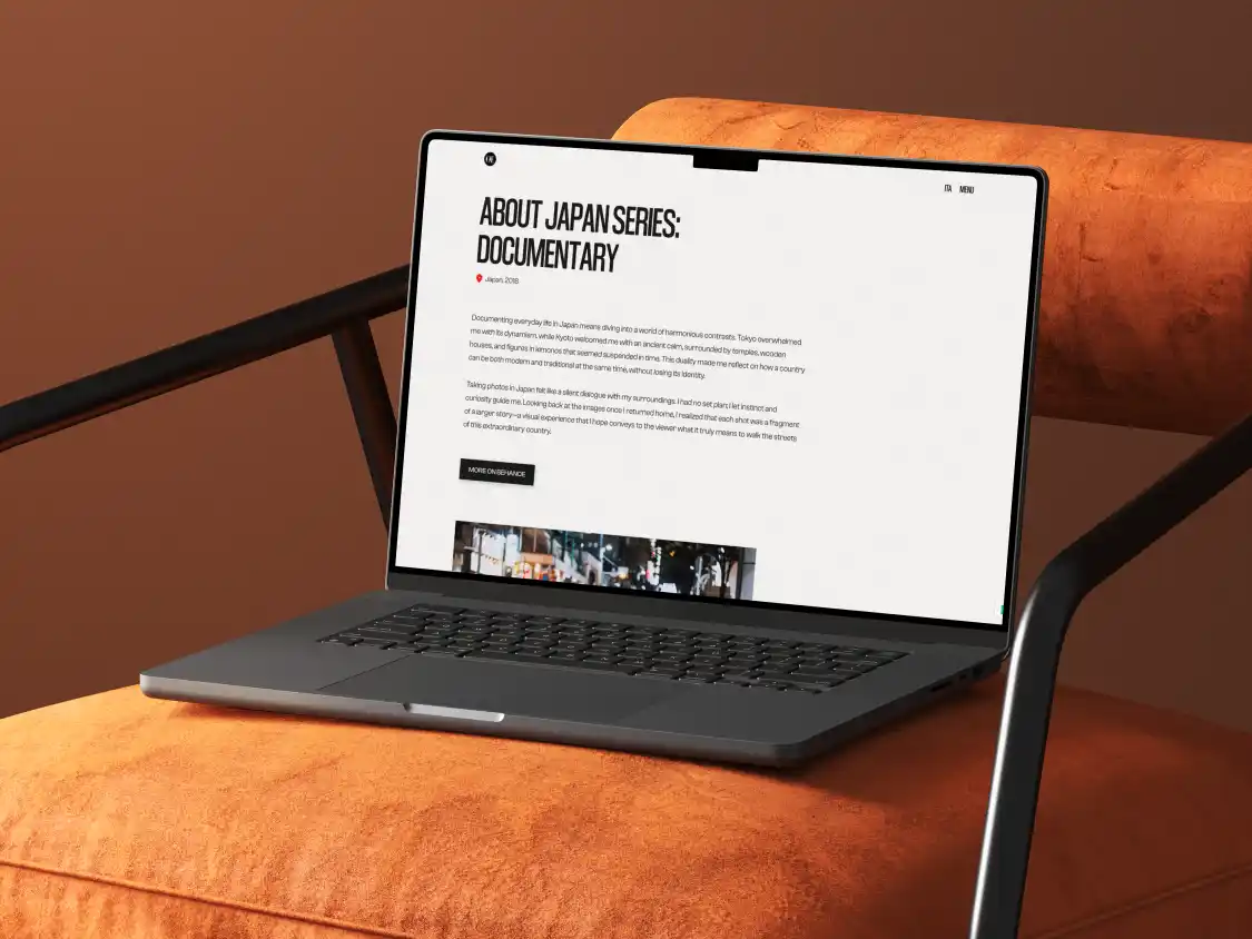 Laptop aperto su una sedia imbottita arancione che mostra una pagina web intitolata 'About Japan Series: Documentary', con un testo che descrive la fotografia in Giappone.